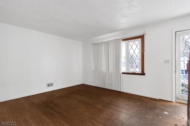 spare room with plenty of natural light, dark hardwood / wood-style flooring, and a textured ceiling