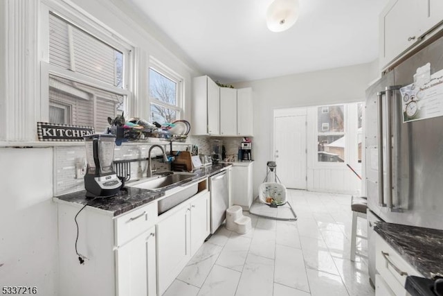 kitchen with sink, white cabinetry, backsplash, dark stone countertops, and stainless steel dishwasher