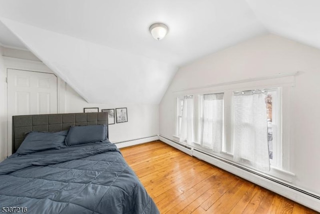 bedroom featuring vaulted ceiling, wood-type flooring, and a baseboard heating unit