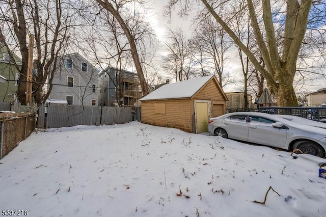 yard layered in snow featuring a garage and an outbuilding