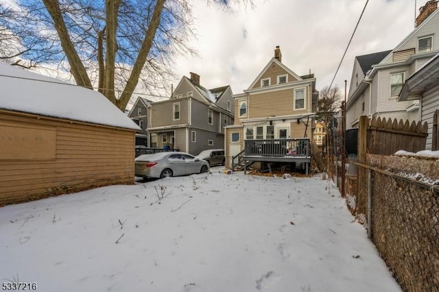 snow covered back of property with a wooden deck