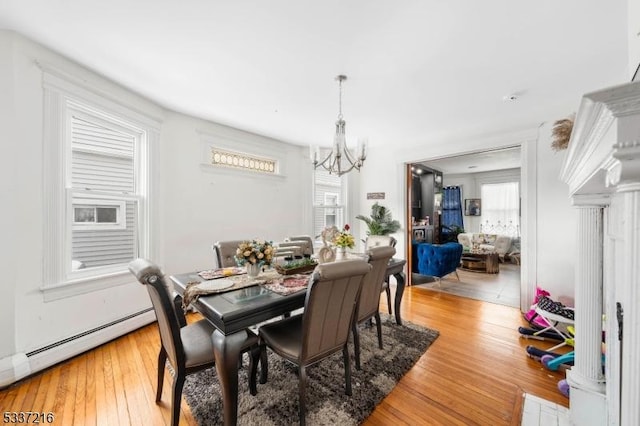 dining room featuring a baseboard radiator, a healthy amount of sunlight, a chandelier, and hardwood / wood-style floors