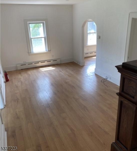 empty room with a baseboard heating unit and light wood-type flooring