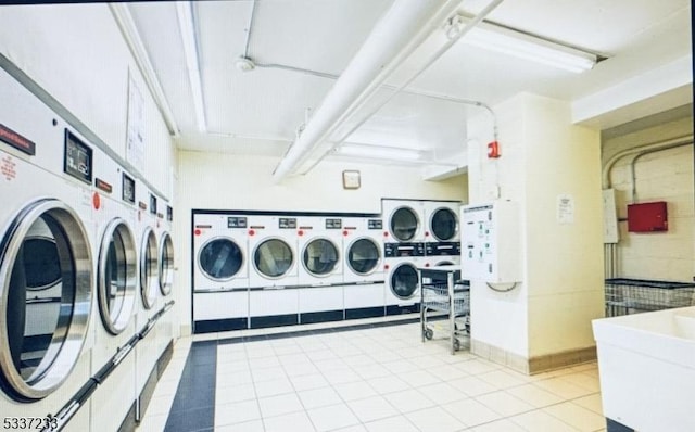 laundry room with light tile patterned flooring, stacked washer and clothes dryer, sink, and washer and clothes dryer