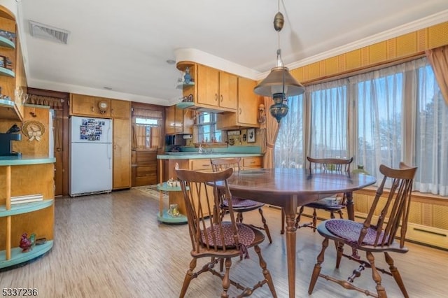 dining space featuring ornamental molding and light wood-type flooring