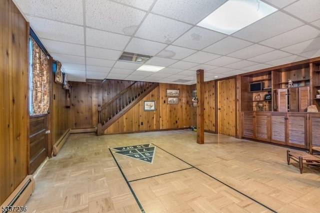 basement with light parquet floors, a baseboard radiator, and wooden walls