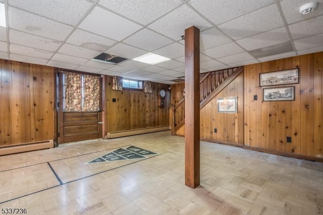 basement with a baseboard heating unit and wooden walls