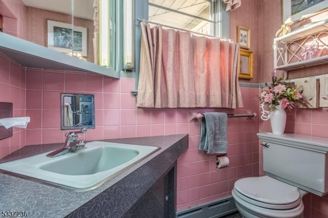 bathroom featuring a baseboard radiator, toilet, curtained shower, and sink