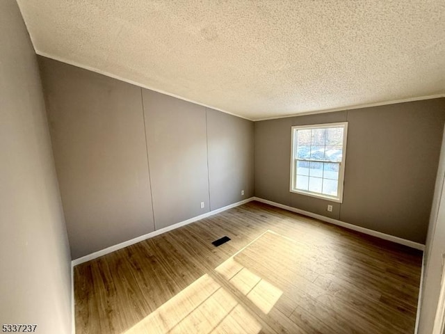 unfurnished room with crown molding, hardwood / wood-style floors, and a textured ceiling