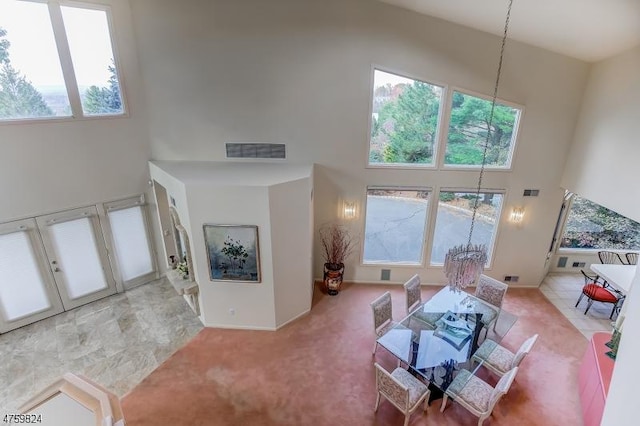 living room with a towering ceiling, a chandelier, and carpet