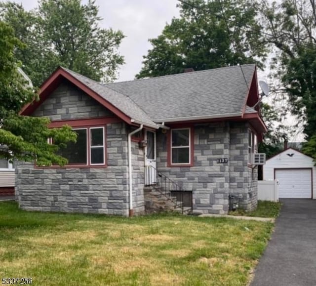 view of front of house featuring a garage, an outbuilding, and a front lawn