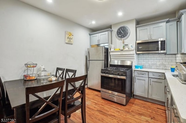 kitchen featuring tasteful backsplash, stainless steel appliances, light hardwood / wood-style floors, and gray cabinetry