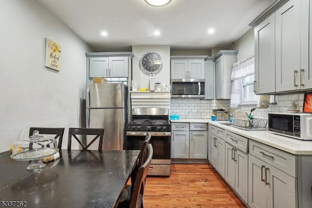 kitchen featuring gray cabinetry, decorative backsplash, light hardwood / wood-style flooring, and appliances with stainless steel finishes