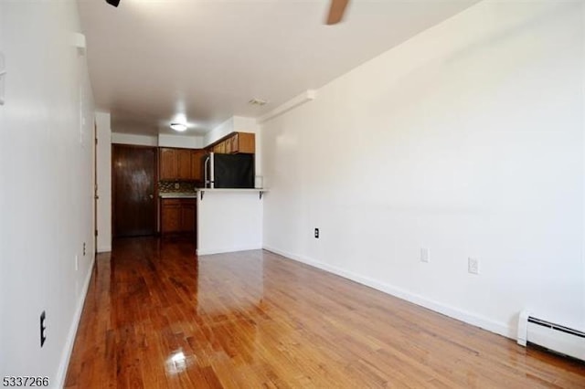 unfurnished living room with wood-type flooring and baseboard heating