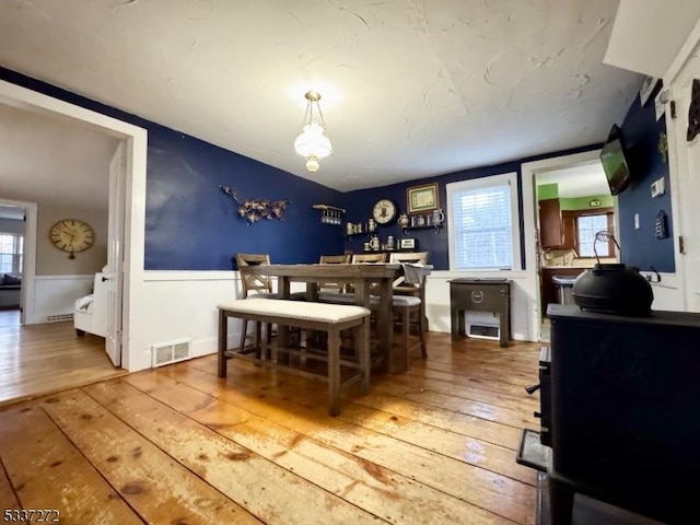 dining room with a wainscoted wall, visible vents, and hardwood / wood-style flooring