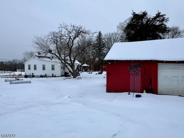 yard layered in snow with a garage and an outdoor structure