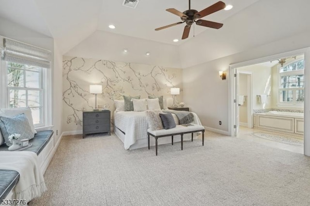 bedroom featuring ceiling fan, light colored carpet, connected bathroom, and multiple windows