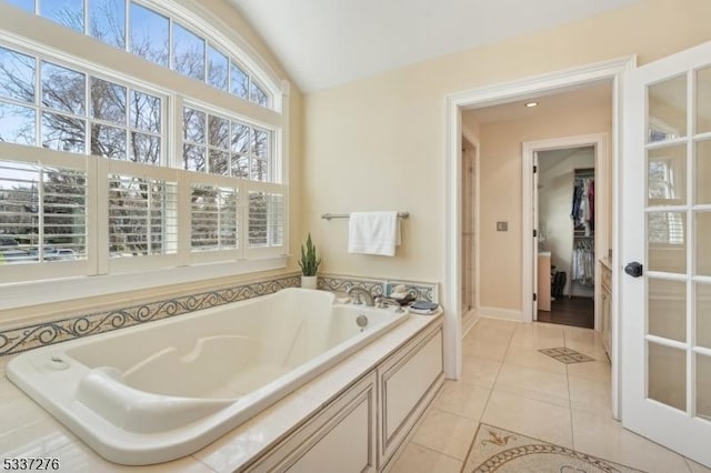 bathroom with vaulted ceiling, tile patterned flooring, and a bathtub