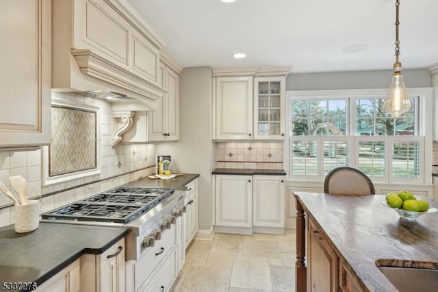 kitchen featuring hanging light fixtures, premium range hood, backsplash, and stainless steel gas stovetop