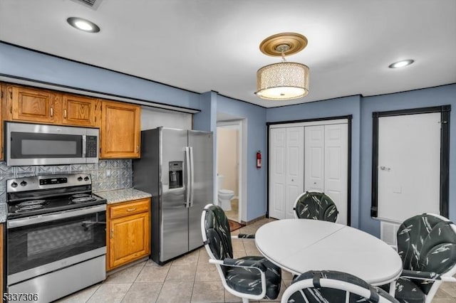 kitchen with hanging light fixtures, decorative backsplash, stainless steel appliances, and light tile patterned flooring