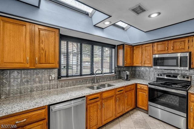 kitchen with sink, backsplash, light tile patterned flooring, and appliances with stainless steel finishes