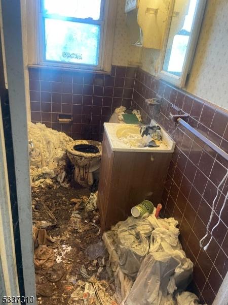 bathroom featuring a healthy amount of sunlight, toilet, and tile walls