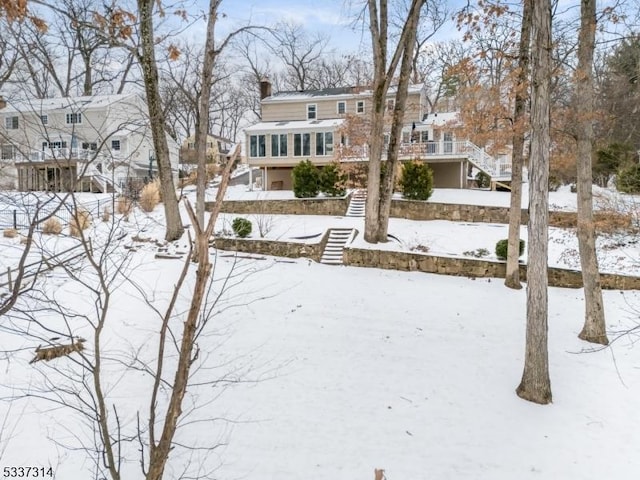 yard layered in snow featuring a sunroom