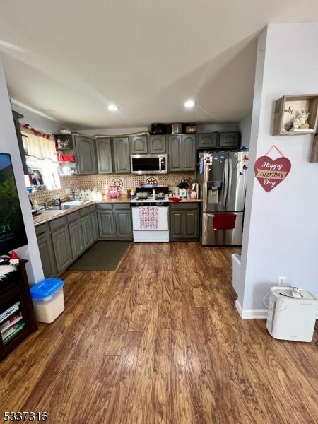 kitchen with appliances with stainless steel finishes, dark wood-type flooring, and decorative backsplash