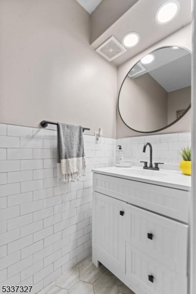 bathroom featuring vanity and tile walls