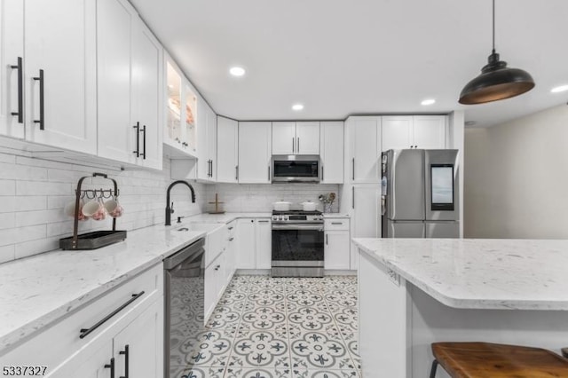 kitchen featuring white cabinetry, stainless steel appliances, decorative light fixtures, and sink