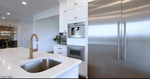 kitchen with white cabinetry, appliances with stainless steel finishes, sink, and decorative light fixtures