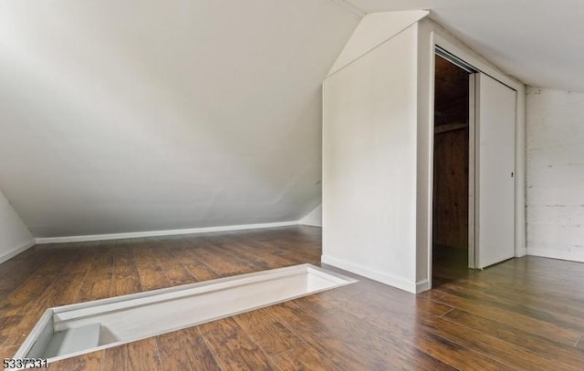 additional living space with vaulted ceiling and dark hardwood / wood-style flooring