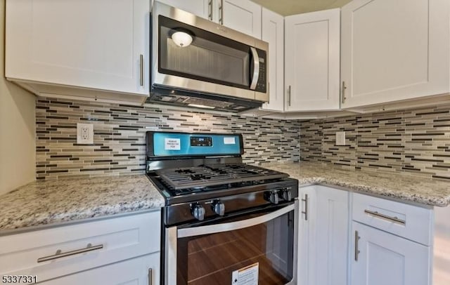 kitchen featuring appliances with stainless steel finishes, tasteful backsplash, light stone counters, and white cabinets