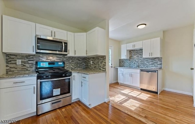 kitchen with white cabinetry, stainless steel appliances, and light hardwood / wood-style flooring