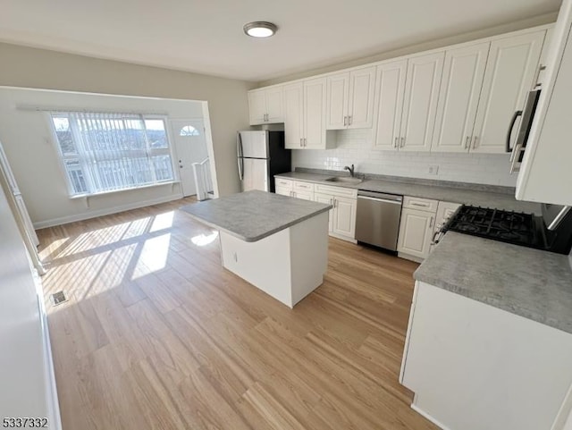 kitchen featuring white cabinetry, tasteful backsplash, a center island, stainless steel appliances, and light hardwood / wood-style floors