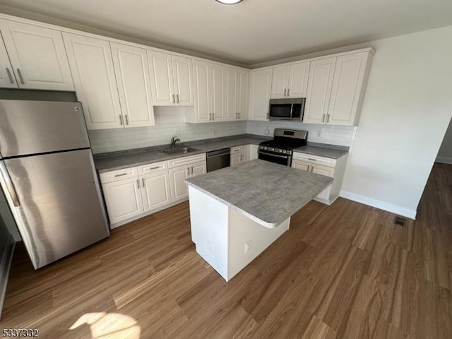 kitchen with appliances with stainless steel finishes, dark hardwood / wood-style flooring, and white cabinets