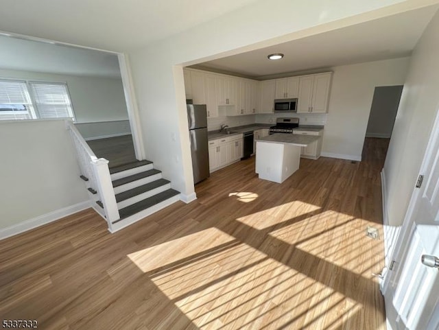 kitchen with white cabinetry, stainless steel appliances, light hardwood / wood-style floors, and a kitchen island