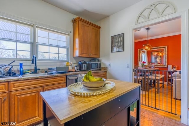 kitchen with butcher block countertops, a sink, a kitchen island, appliances with stainless steel finishes, and brown cabinetry