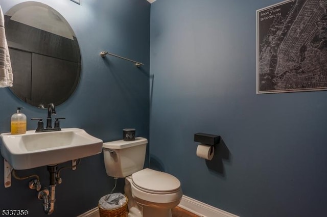 bathroom with toilet, baseboards, and a sink