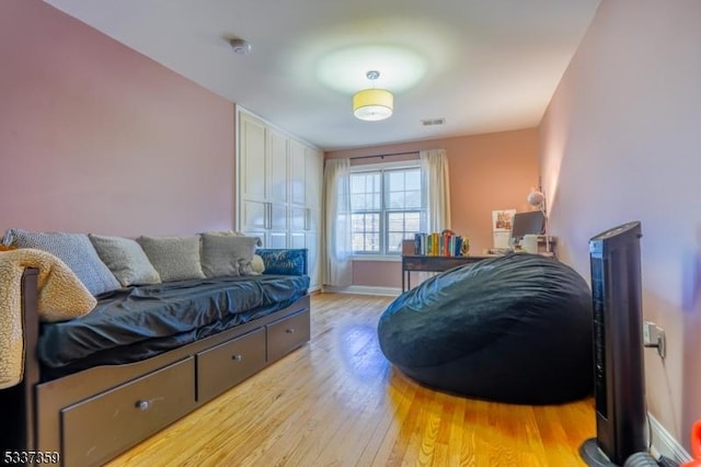 bedroom with light wood-style floors, visible vents, and baseboards