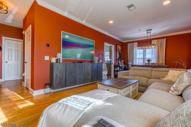 living area with ornamental molding, visible vents, baseboards, and wood finished floors