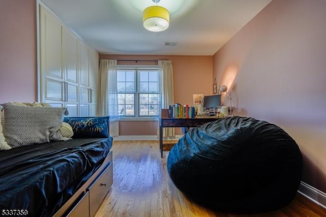 bedroom with light wood-style floors, visible vents, and baseboards