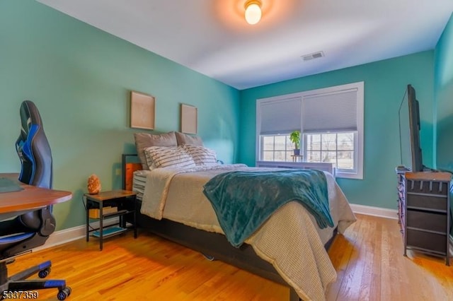 bedroom featuring light wood-style floors, visible vents, and baseboards