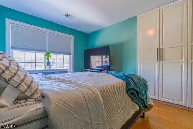 bedroom featuring a closet, visible vents, and light wood-style floors