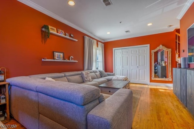 living area with ornamental molding, wood finished floors, visible vents, and recessed lighting