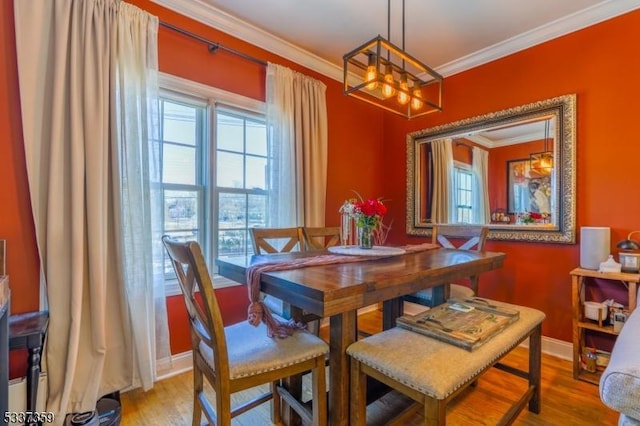 dining area with light wood-style floors, baseboards, and crown molding