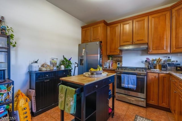 kitchen featuring stainless steel appliances, butcher block counters, brown cabinets, and under cabinet range hood