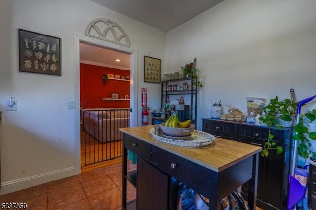 interior space featuring baseboards, a center island, tile patterned flooring, dark cabinetry, and a kitchen bar