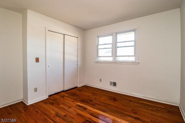 unfurnished bedroom with dark hardwood / wood-style floors and a closet