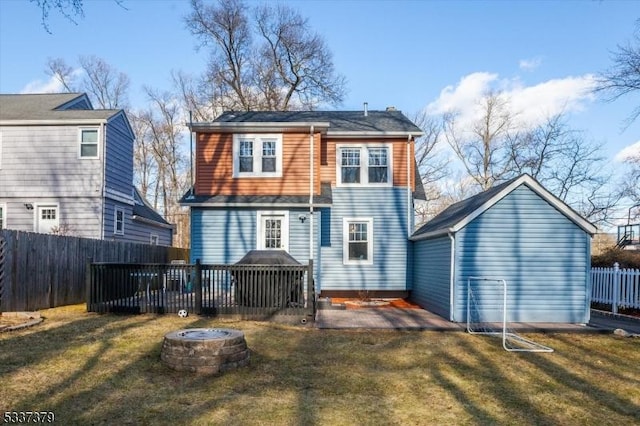 rear view of property with a yard, a fire pit, and a deck